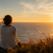 Personne contemplant un paysage d’été au coucher du soleil dans une ambiance douce et introspective